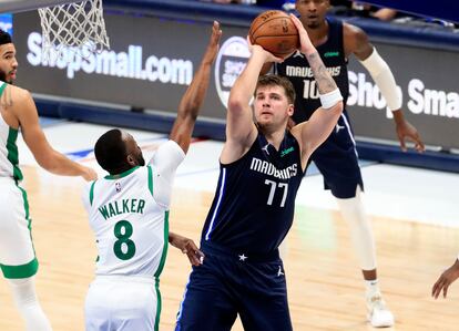 Doncic lanza un triple pese a la oposición de Kemba Walker.