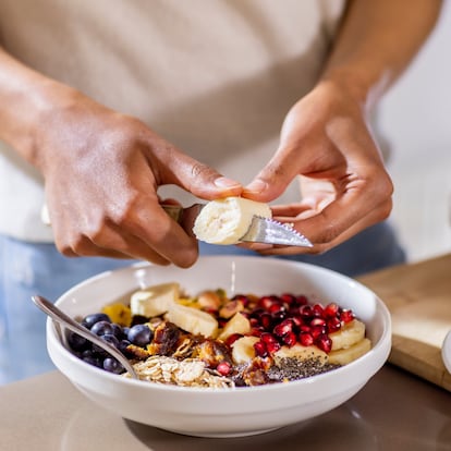 close up of woman making healthy breakfast in kitchen with fruits and yogurt