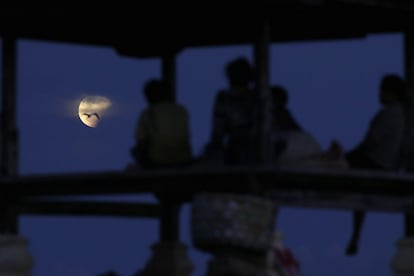 Un grupo de personas contemplan el eclipse que se produce cuando el Sol, la Tierra y la Luna se alinean de manera que la Luna pasa a través de la sombra de la Tierra, en Denpasar, Bali (Indonesia).