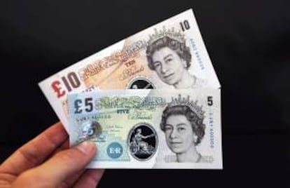Una persona sostiene unos billetes de muestra de cinco y diez libras fabricados de un polímero plástico durante una rueda de prensa en el Banco de Inglaterra en Londres, Reino Unido, hoy, martes 10 de septiembre de 2013.