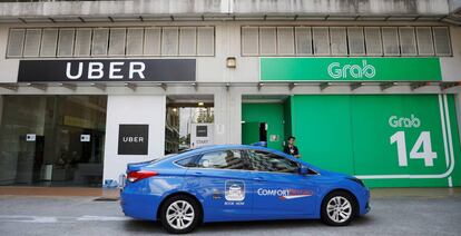 Un taxi ComfortDelgro pasa por delante de oficinas de Uber y Grab en Singapur.