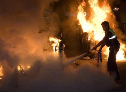 Un agente trata de sofocar el fuego de dos contenedores provocado por los radicales.