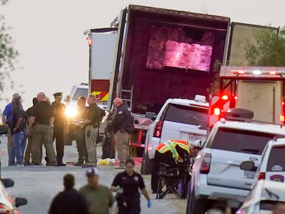 Police officers and first responders stand next to the trailer in which 53 migrants died, in San Antonio.