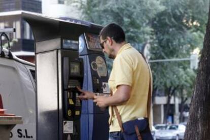 Un usuario saca un tique en un parquímetro nuevo con el viejo al fondo.