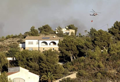 Los medios aéreos se centraron en proteger las zonas más densamente pobladas para evitar daños humanos y materiales. En la imagen, un helicóptero con una canasta para la extinción sobrevuela la zona del incendio. Antes de caer la noche, comenzaban los desalojos preventivos que acabaron con cerca de 1.400 personas desplazadas.