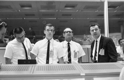 Glynn Lunney (second left) standing at the flight director's console of NASA’s mission control center on July 1966. 