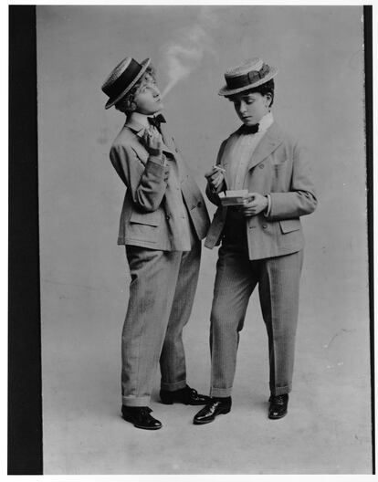 Anuncio de principios del siglo XX en el que se ve a dos mujeres que, vestidas de hombre, disfrutan de un cigarrillo.