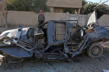 Un iraquí observa un coche destrozado en Bagdad.