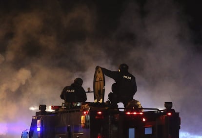 Agentes policiales vigilan la localidad durante la primera noche de toque de queda que, según ha dicho el gobernador del estado de Misuri, Jay Nixon, podría durar varios días.