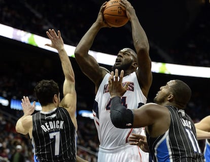 Ivan Johnson, de los Atlanta Hawks, captura un rebote ante Glen Davis y J.J. Redick, de los Orlando Magic