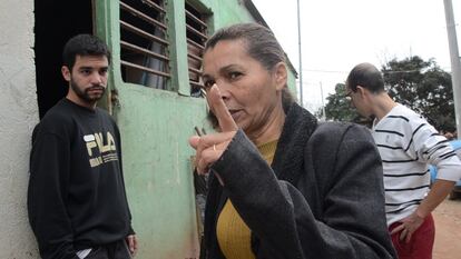 Lia, na frente da sede da Associação da Vila Nova Esperança, fala com os voluntários que chegam à comunidade para colaborar. Lucas escuta atentamente seu discurso da porta.