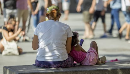 Una mujer y una niña, este lunes en un banco en Sevilla.