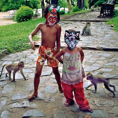 Dos niños vagabundos juegan con unas máscaras en el camino de subida al templo de Watphnom, rodeados de monos.