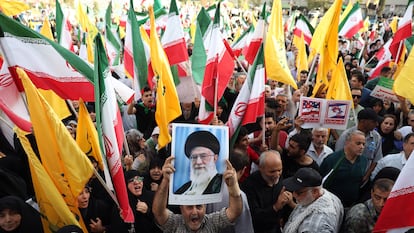 Un iraní sostiene un retrato del líder supremo iraní, el ayatolá Alí Jamenei, entre banderas nacionales de Irán durante una manifestación en Teherán, el pasado martes.
