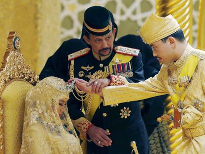 El sultán de Brunei, Hassanal Bolkiah, sostiene el brazo de su hijo, el príncipe Abdul Malik, para bendecir a la nueva esposa de Malik, Dayangku Raabi'atul 'Adawiyyah Pengiran Haji Bolkiah, en su boda en el Palacio Nurul Iman en Bandar Seri Begawan, el 12 de abril. 2015.