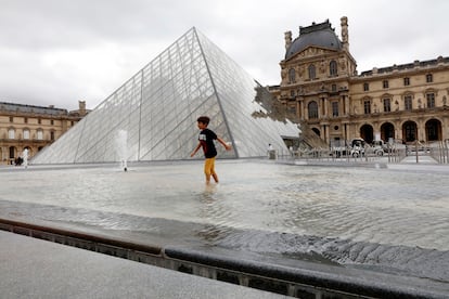 Un niño juega en la fuente junto a la entrada del museo del Louvre.