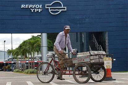 Un comerciante boliviano pasa en bicicleta frente a las instalaciones de Repsol en Santa Cruz.