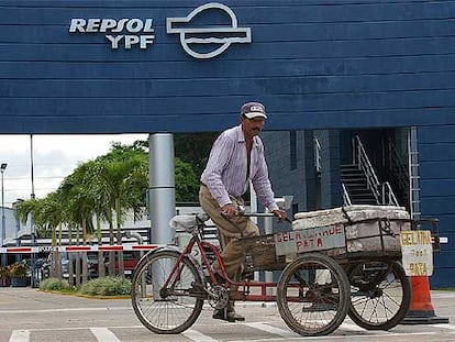 Un comerciante boliviano pasa en bicicleta frente a las instalaciones de Repsol en Santa Cruz.