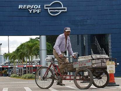 Un comerciante boliviano pasa en bicicleta frente a las instalaciones de Repsol en Santa Cruz.