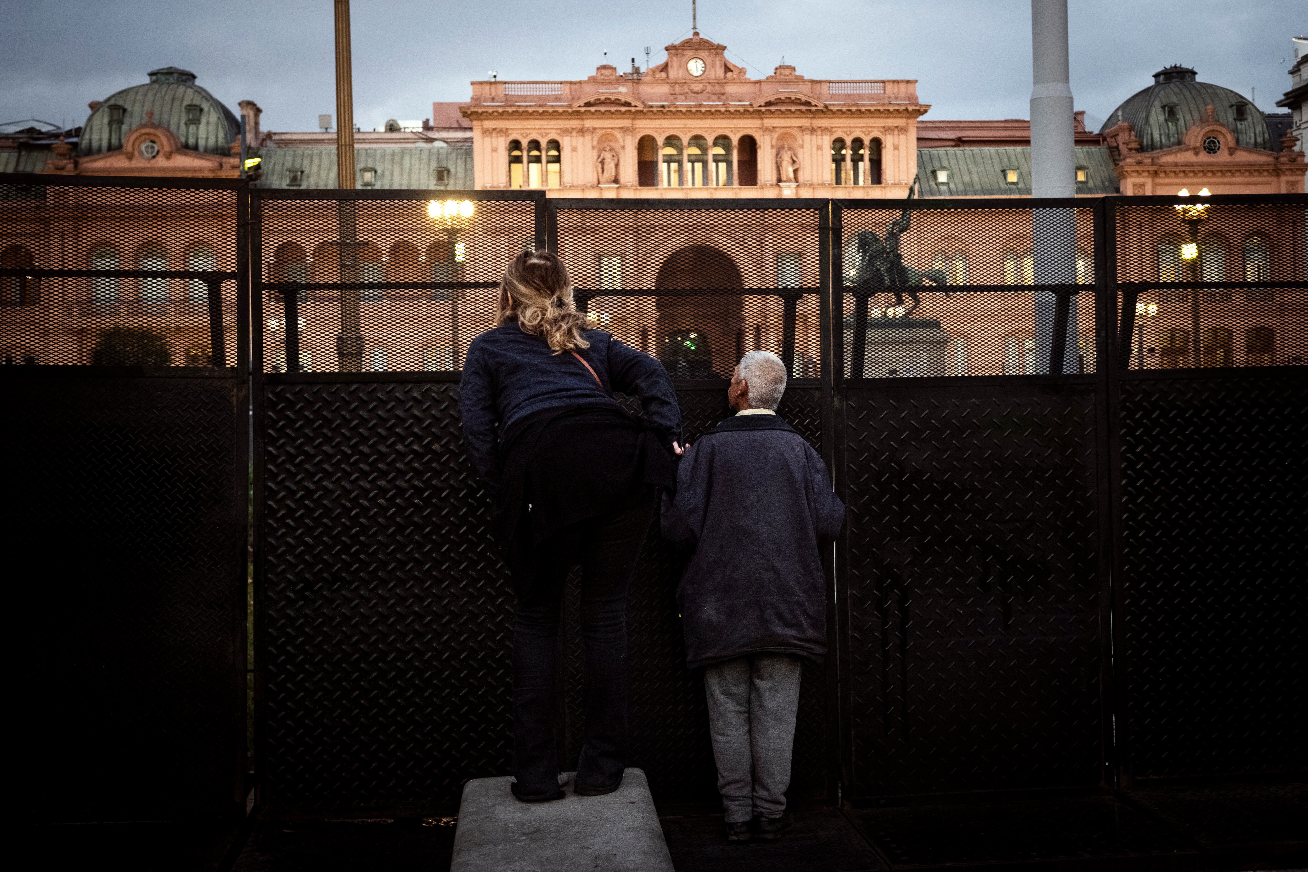 Dos personas protestan en el vallado que rodea la Casa de Gobierno  en Plaza de Mayo para pedir por la liberación de los detenidos.