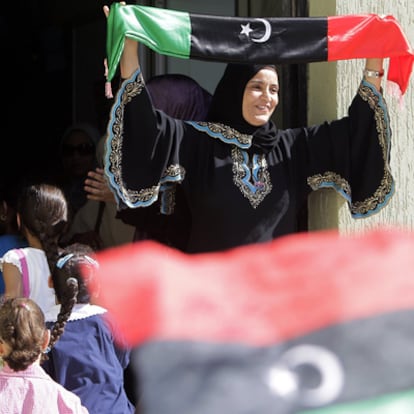 Una maestra sostiene una bandera libia del bando rebelde, en el primer día de colegio en Trípoli.