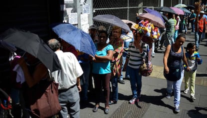 Un grupo de personas hace cola a las puertas de un supermercado en Caracas.