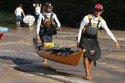 Etxeberria (a la derecha) y Erkiaga llegan ayer al puerto de San Sebastián y portan la <i>kayak</i> de mar con la que han dado la vuelta a la península.