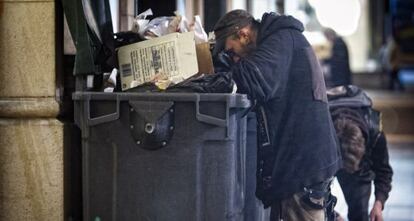 Dos personas buscan comida de entre la basura en Barcelona. 