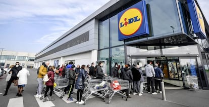 Ciudadanos protegidos con máscaras hacen cola delante de un supermercado en la ciudad de Casalpusterlengo, de donde el Gobierno ha prohibido salir.