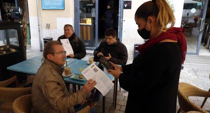 Una camarera pide certificado a los clientes en una mesa en la terraza de un bar en Málaga.