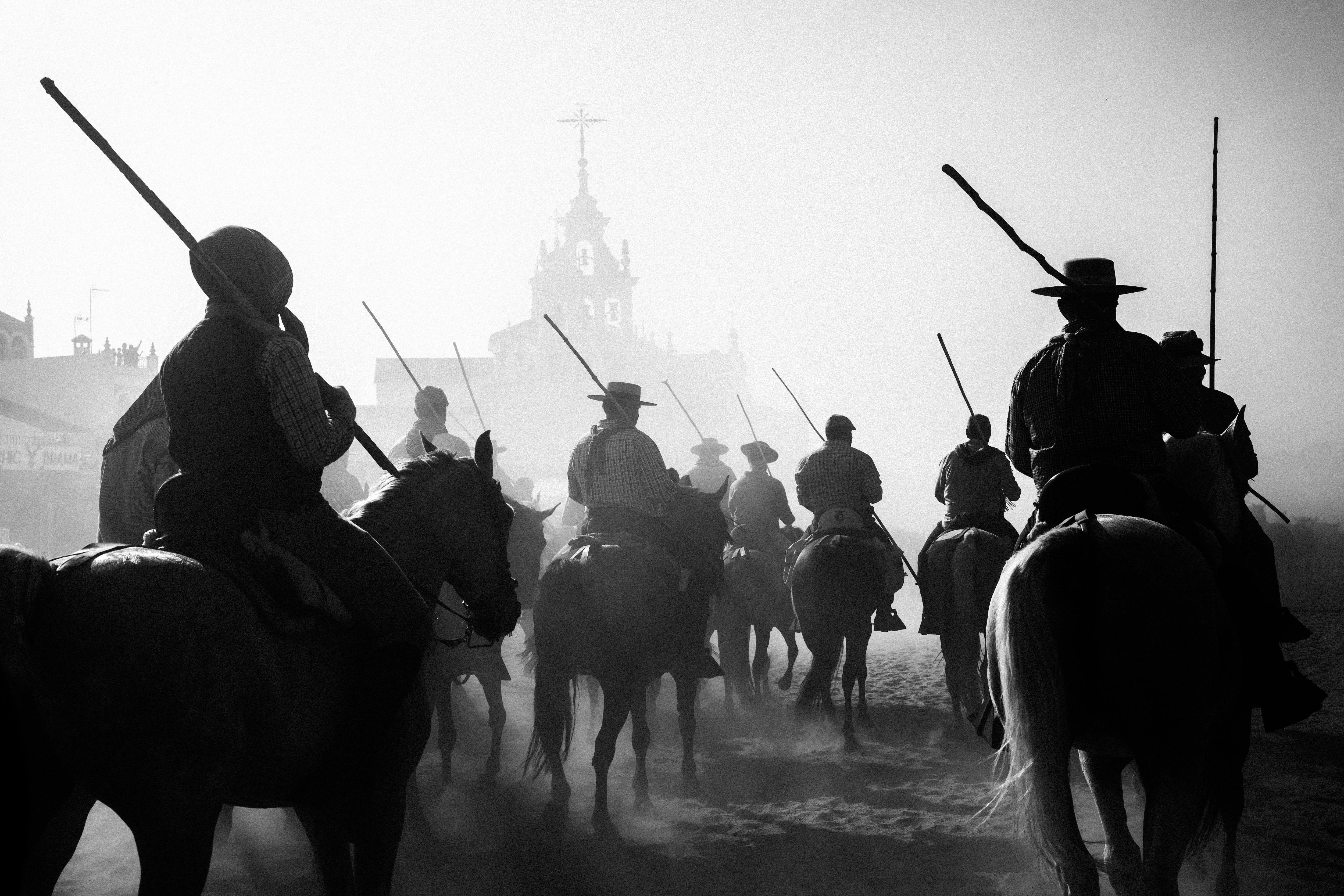 Un grupo de yegüerizos con la ermita de la Virgen del Rocío al fondo.