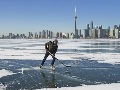Un hombre juega al hockey con el 'skyline' de Toronto al fondo.