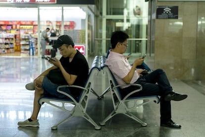 Ciudadanos de la China usan sus móviles mientras esperan al tren en la estación de Tianjin.