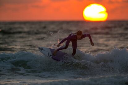 Un surfista coge una ola, al atardecer, en la playa de Fistral el primer día del Boardmasters surf and music en Newquay, Cornwall, Reino Unido.