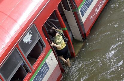 Una mujer sube al autobús, rodeado por la riada