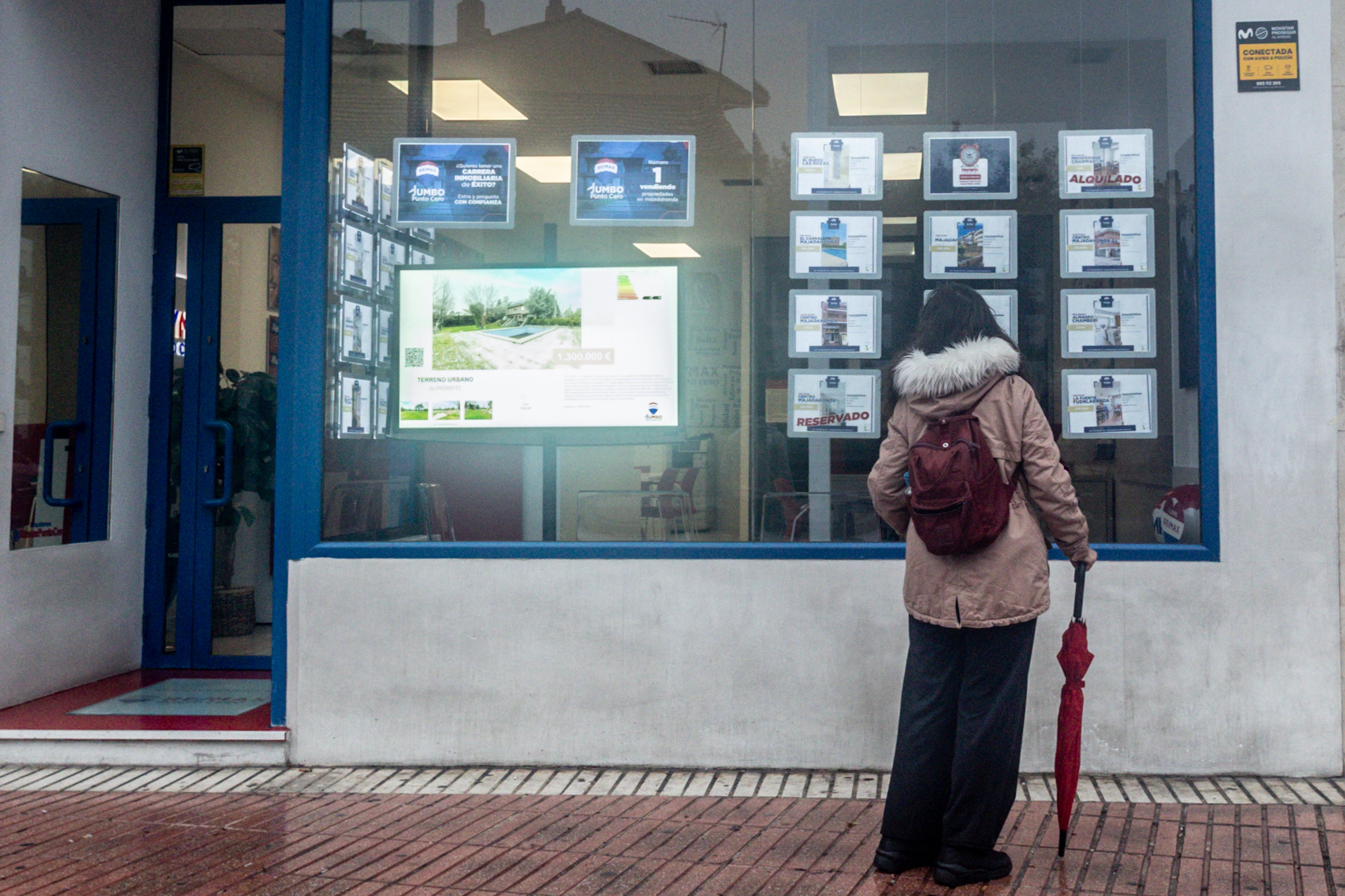 Una mujer mira anuncios en el escaparate de una agencia inmobiliaria.