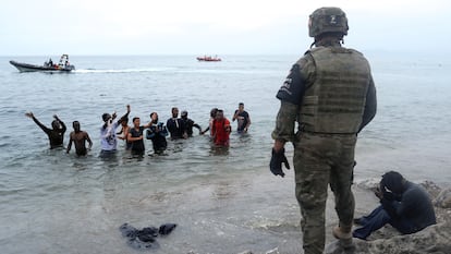 Un militar español frente a un grupo de marroquíes que intentan entrar en Ceuta a través del mar.