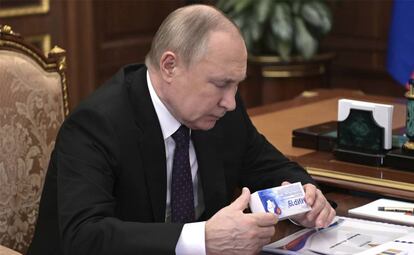 El presidente de Rusia, Vladimir Putin, mirando una caja de un medicamento en una conferencia el 15 de marzo