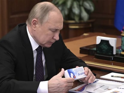 El presidente de Rusia, Vladimir Putin, mirando una caja de un medicamento en una conferencia el 15 de marzo