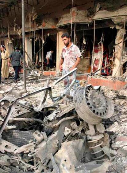 Un hombre contempla los restos del coche bomba utilizado en el atentado contra el centro comercial de Kirkuk.
