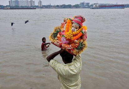 Un devoto carga con la diosa hindú Ganesha, en una inmersión en las aguas del río Ganges, el segundo día del festival Chaturthi en Calcuta (India).