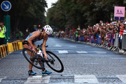 Manami Iijima, de Guam, recoge su bicicleta después de caer durante el triatlón individual femenino.