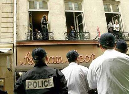 Varios periodistas del semanario francés <i>Le Canard  Enchaîné</i> se asoman a los balcones de la redacción después de impedir un registro judicial