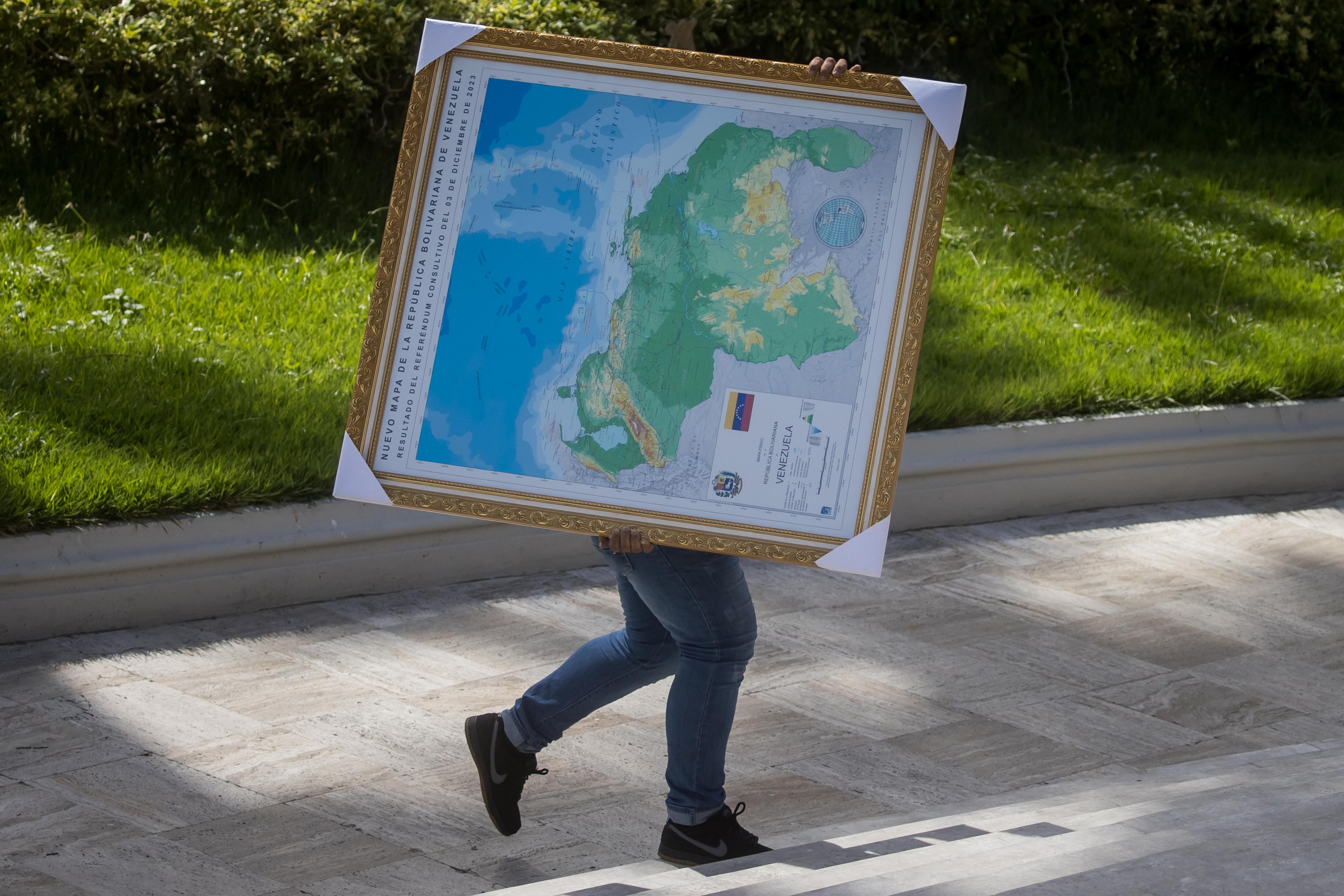 Un hombre carga el mapa de Venezuela con la adhesión del Esequibo, en uno de los jardines del Palacio Federal Legislativo en Caracas (Venezuela).