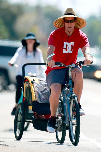 A Adam Sandler le gusta pedalear en familia. Con gorro y gafas para protegerse del sol, el actor pasea en bicicleta por Malibu con su mujer y sus hijos.