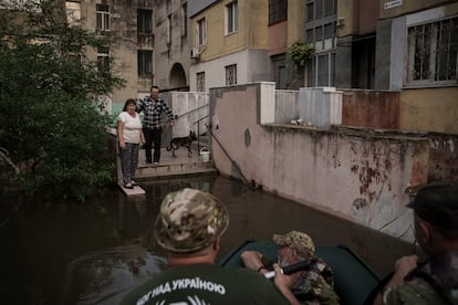 Dos vecinos hablan con un grupo de militares en el exterior de un bloque de viviendas en la ciudad de Jersón, el miércoles.