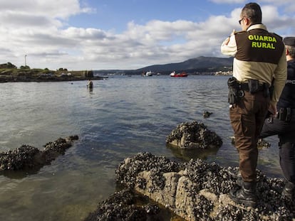 Un guardia rural y un agente de Policía vigilan en los arenales de Boiro (A Coruña) que no haya ningún mariscador furtivo cogiendo ejemplares.