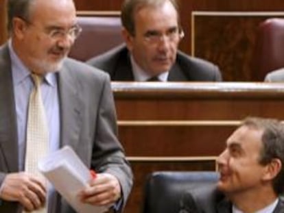 Pedro Solbes conversa con Rodríguez Zapatero mientras se dirige al estrado del Congreso.
