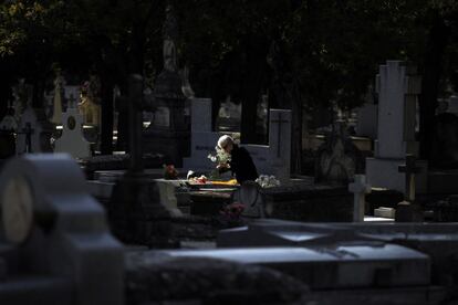 Una mujer coloca flores sobre una tumba en el cementerio de La Almudena de Madrid. Este cementerio recibe su nombre de la Virgen de la Almudena, patrona de Madrid.