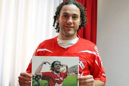 Milito posa con la camiseta y una foto de su etapa anterior en el Independiente.